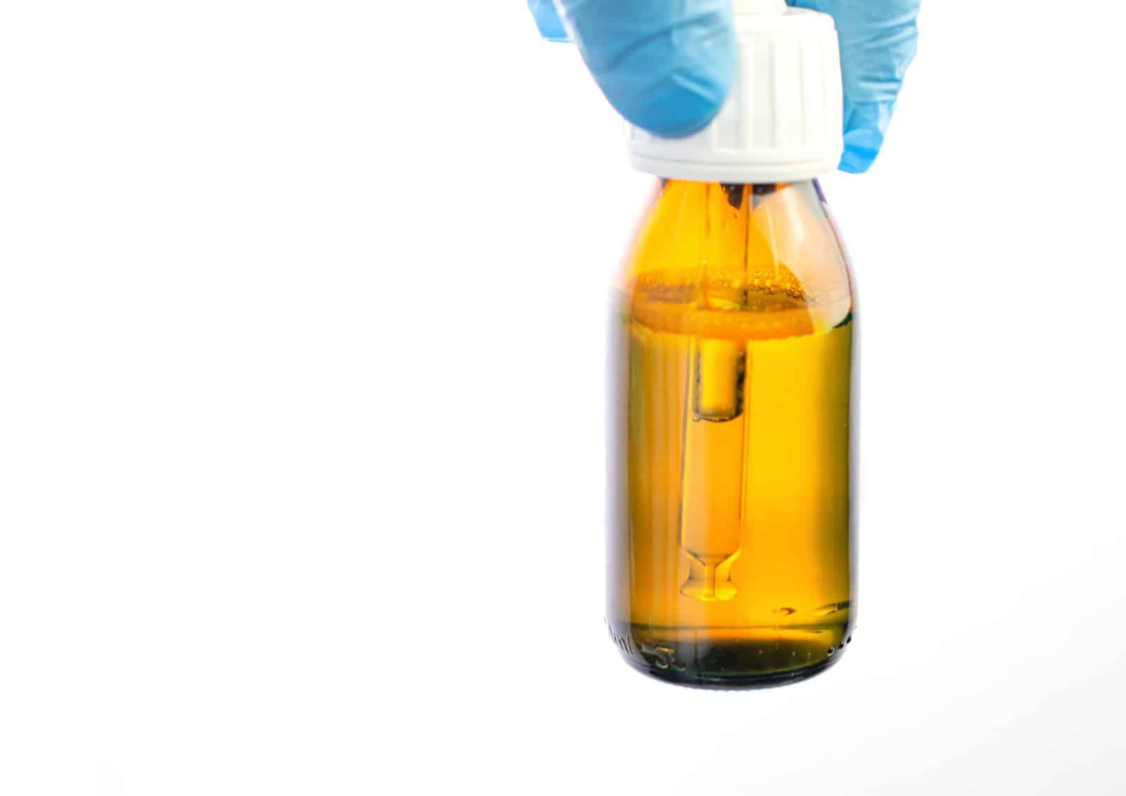 Bottle with dropper in the hands of the doctor in the laboratory White background