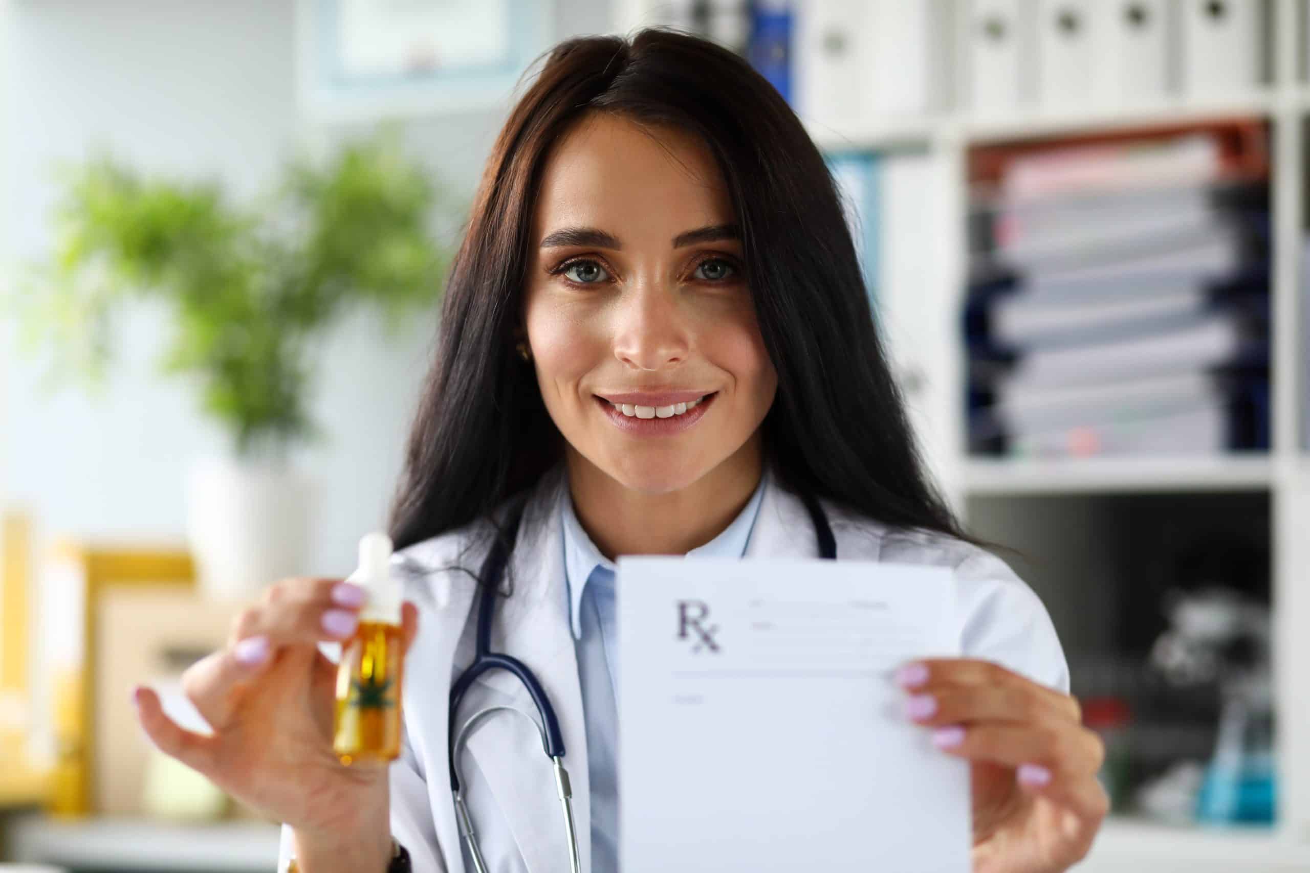 Pretty cheerful female GP giving to patient dropper jar of cannabis concentrate oil during consultation close-up