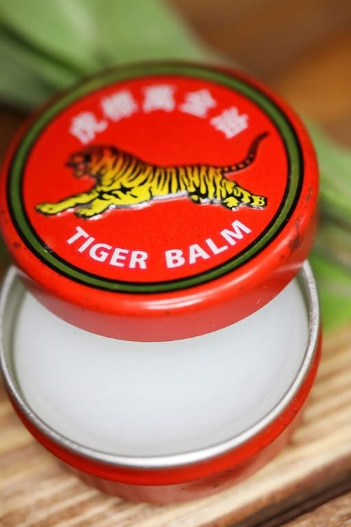 Gros plan du couvercle d'un pot contenant une pommade analgésique asiatique à base de baume du tigre.