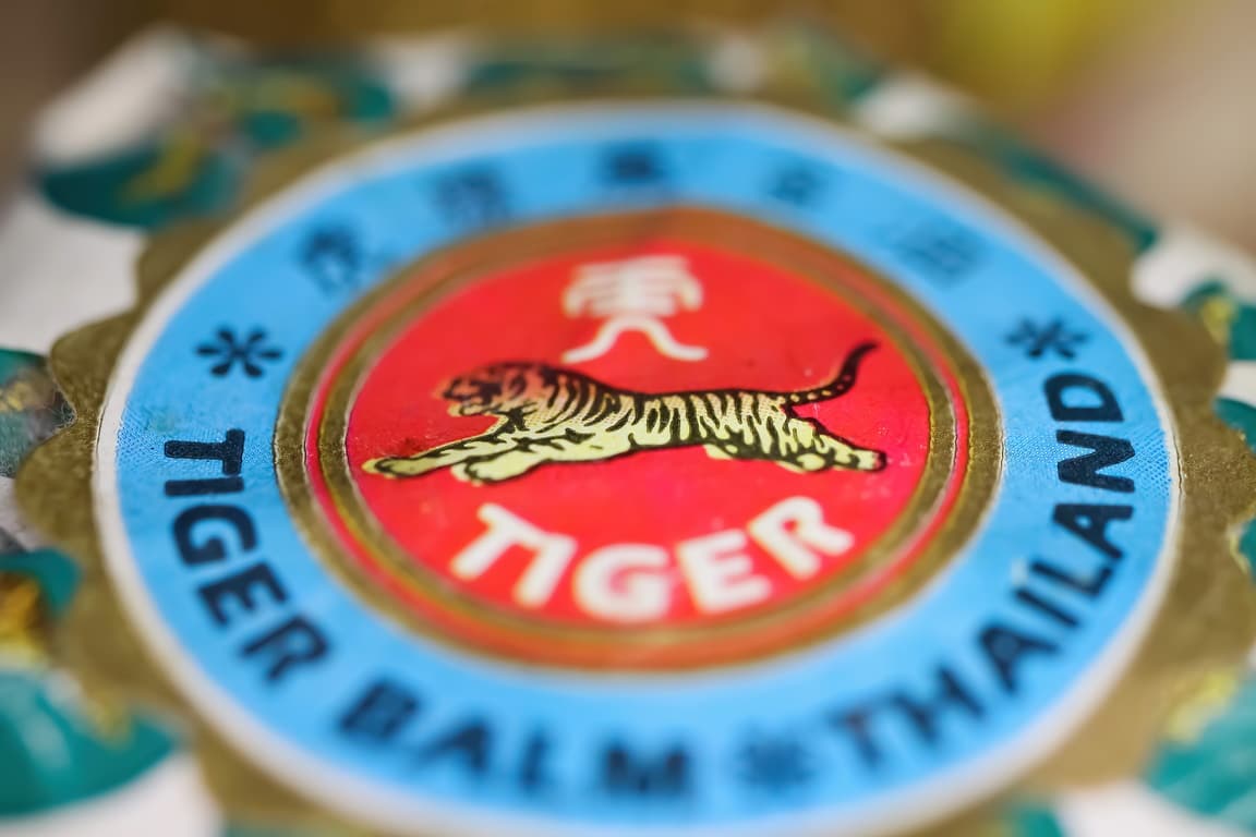 Gros plan du couvercle d'un pot contenant une pommade analgésique asiatique à base de baume du tigre.