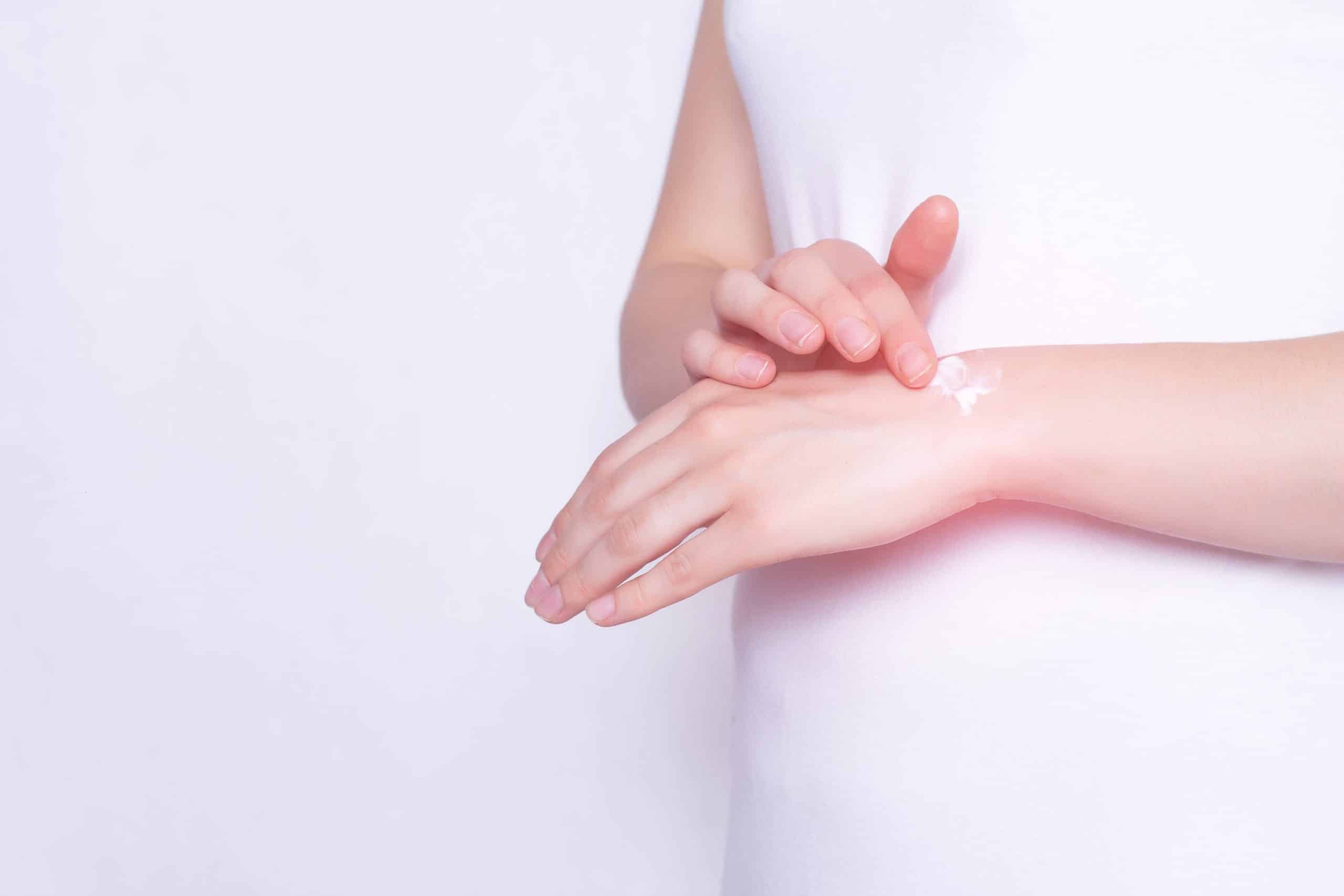The girl rubs the healing ointment into the wrist joint against pain and inflammation in the joint, White background, copy space