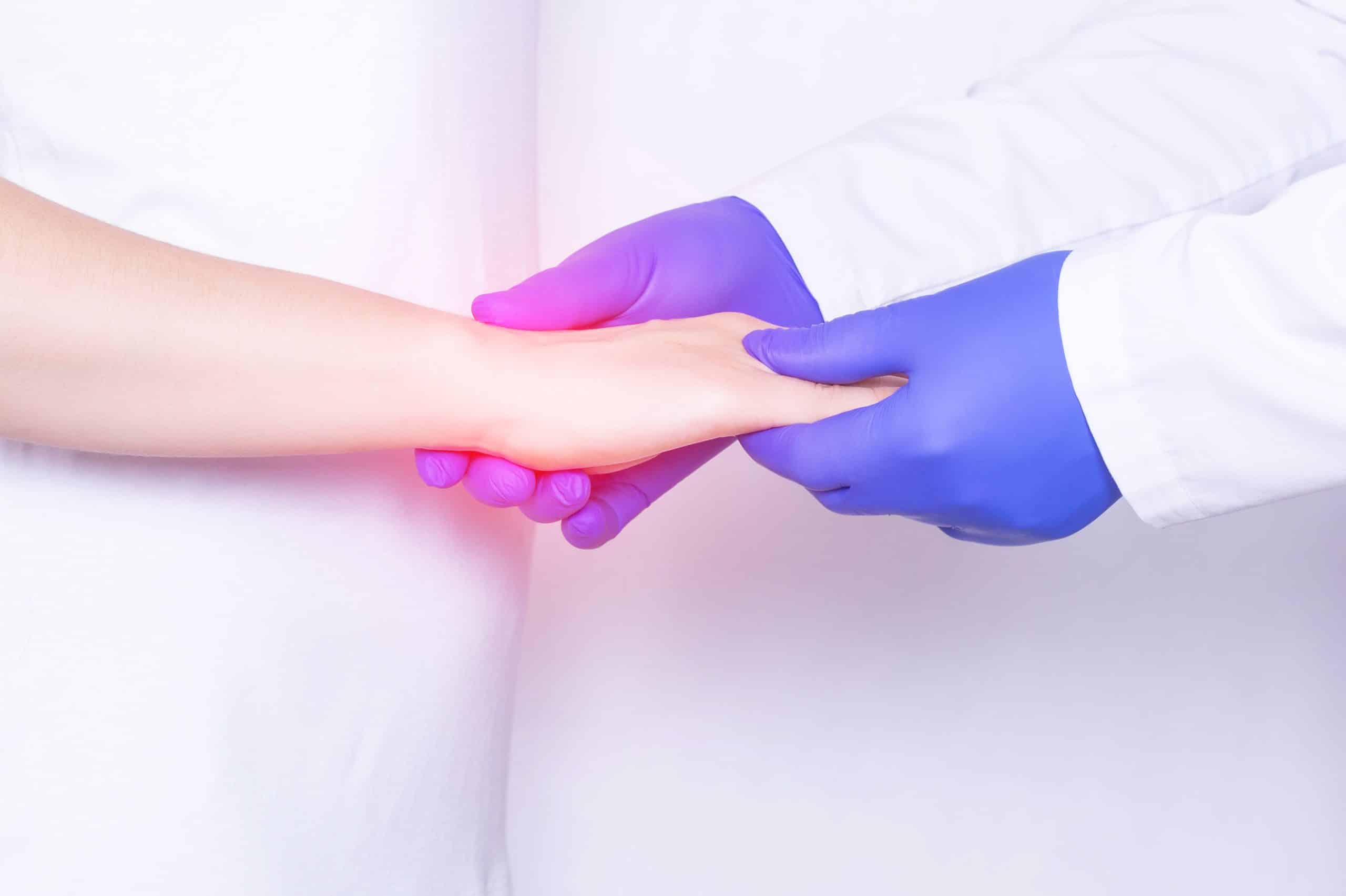 Doctor examines a girl's wrist joint for sprain, inflammation and pain in her wrist, close-up, arthrosis, chronic pain